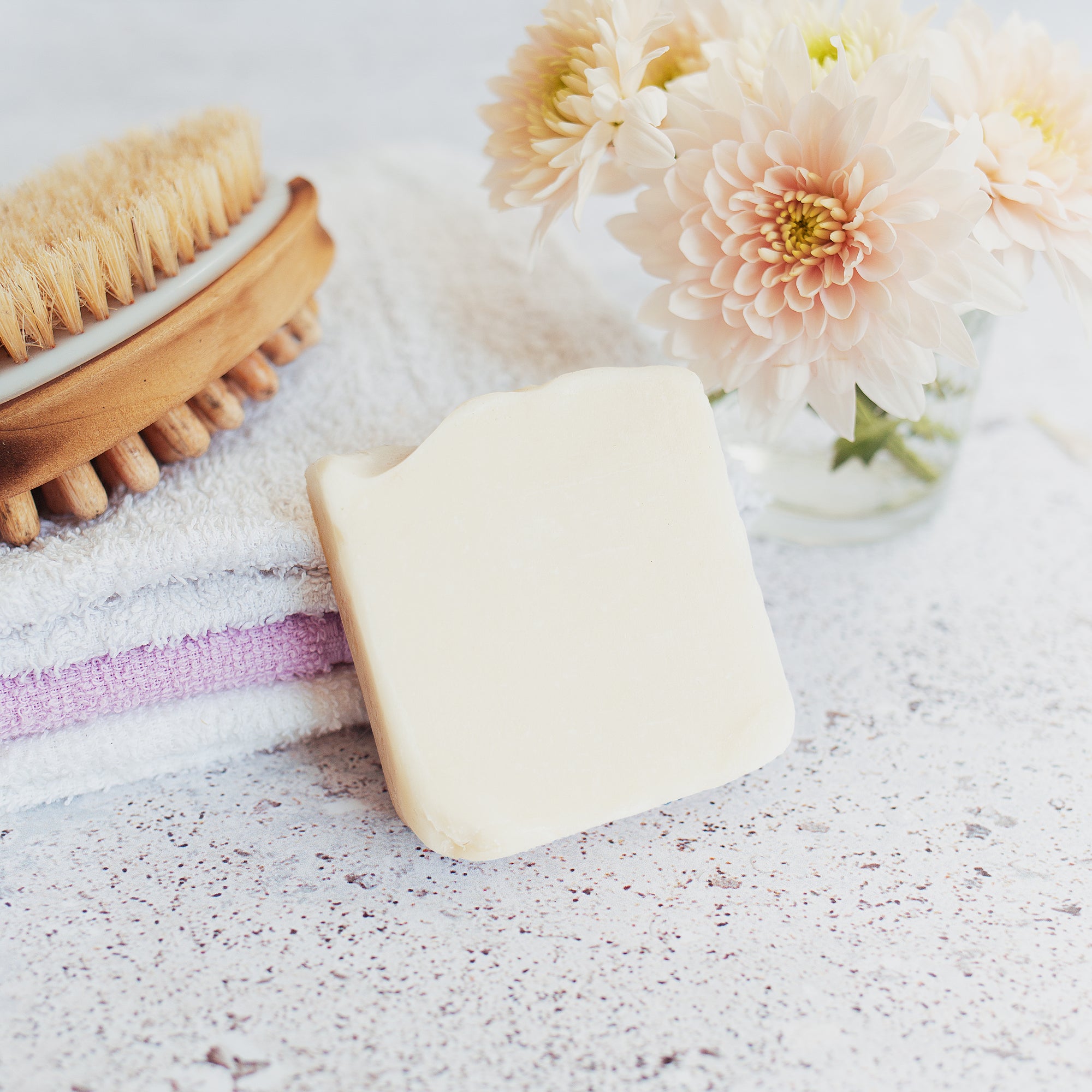 Goat Milk Soap - Lifestyle on top of towels and next to brush and flowers